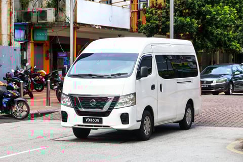 White passenger van Nissan NV350 Caravan in the city street